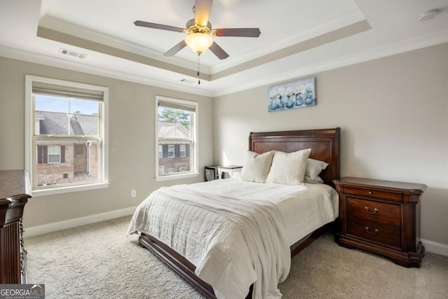 bedroom with crown molding, a tray ceiling, light colored carpet, and ceiling fan