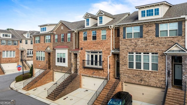 multi unit property with brick siding, stairway, a residential view, and a garage