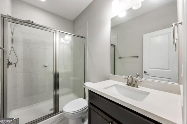 bathroom with vanity, toilet, and a shower with shower door