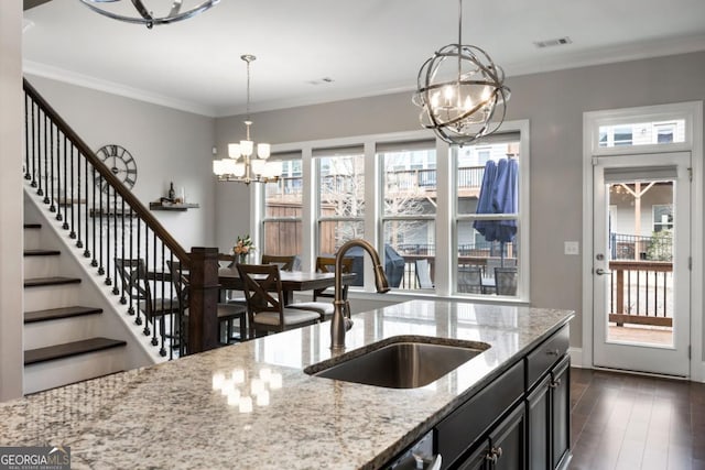 kitchen featuring sink, hanging light fixtures, light stone countertops, and a chandelier