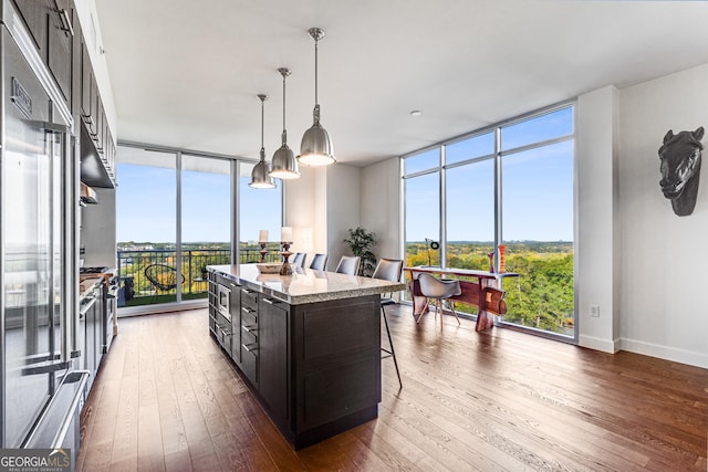 kitchen featuring a kitchen island, floor to ceiling windows, hanging light fixtures, and dark brown cabinets