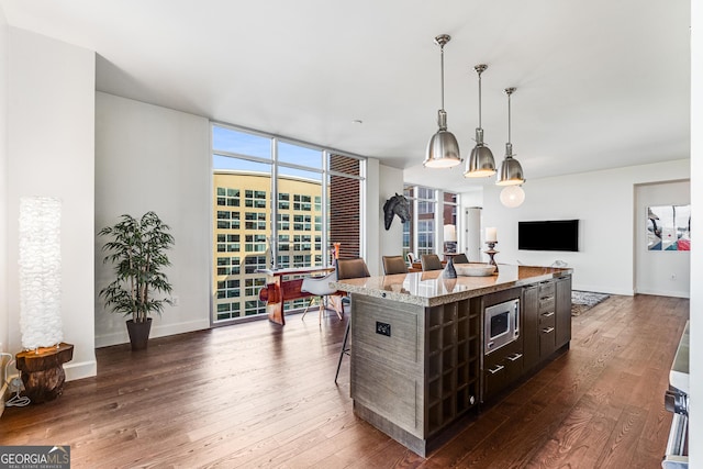 kitchen featuring hanging light fixtures, a center island, a kitchen bar, and dark wood-type flooring