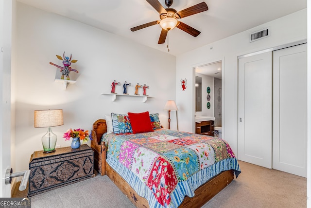 carpeted bedroom featuring ceiling fan, ensuite bath, and a closet