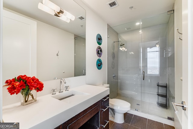 bathroom featuring toilet, a shower with door, tile patterned flooring, and vanity