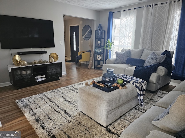 living room featuring dark wood-type flooring and a textured ceiling