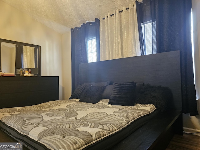 bedroom with dark hardwood / wood-style flooring, vaulted ceiling, and a textured ceiling