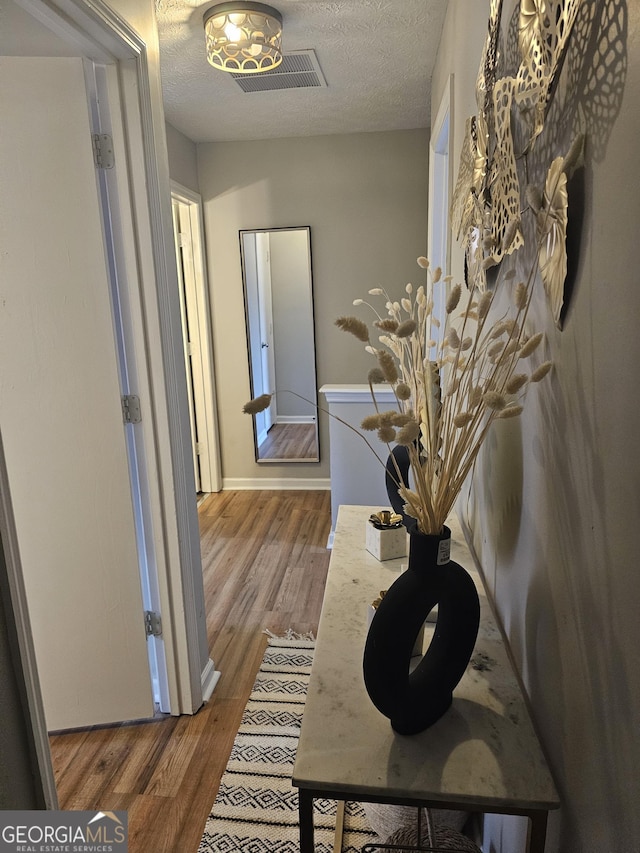 corridor with hardwood / wood-style floors and a textured ceiling