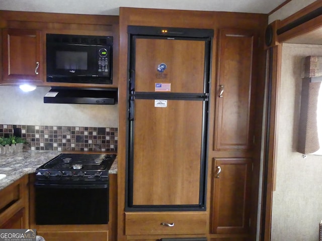 kitchen with light stone counters, decorative backsplash, black appliances, and exhaust hood