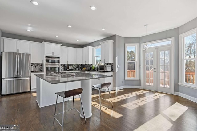 1331 Dayspring Trce, Lawrenceville, GA 30045 - kitchen featuring a kitchen island, white cabinetry, appliances with stainless steel finishes, and a breakfast bar area