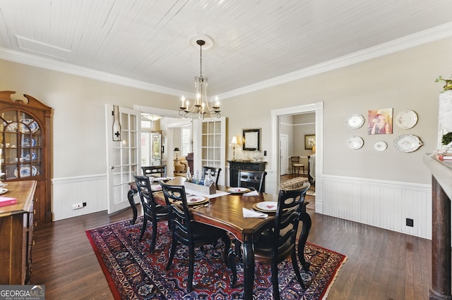 dining area featuring a wainscoted wall, ornamental molding, dark wood-style floors, and an inviting chandelier