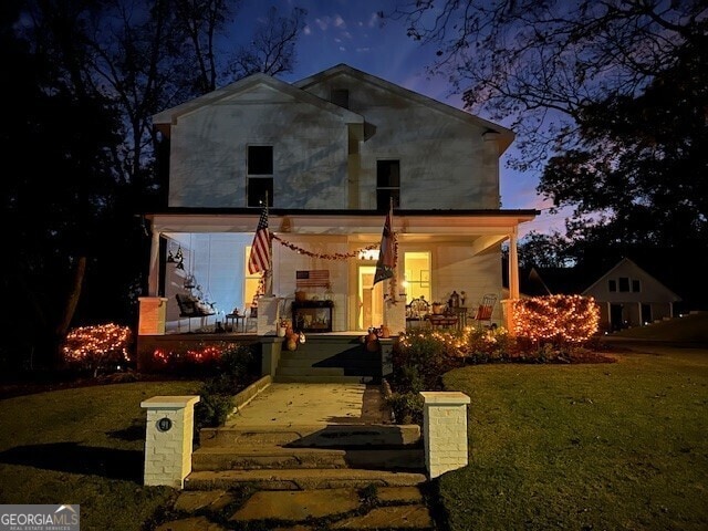 rear view of house featuring a porch and a lawn