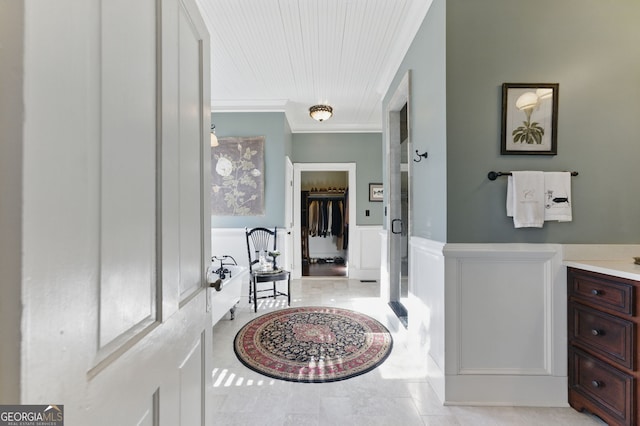 bathroom with a wainscoted wall, ornamental molding, and a decorative wall