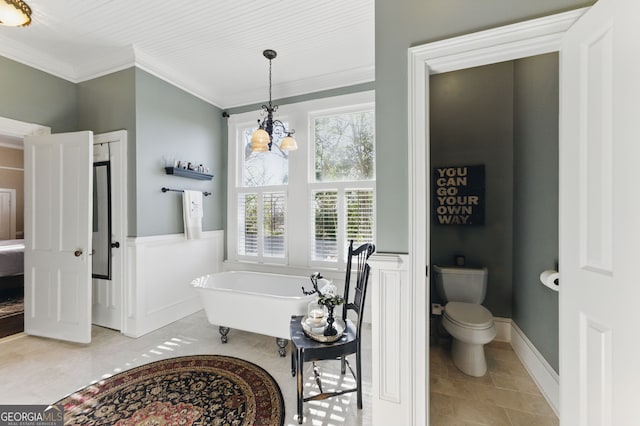 full bathroom with a soaking tub, wainscoting, crown molding, and toilet