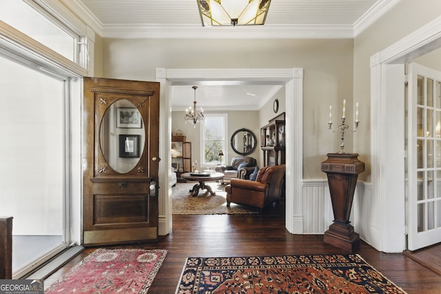 entrance foyer with ornamental molding, hardwood / wood-style flooring, wainscoting, and an inviting chandelier