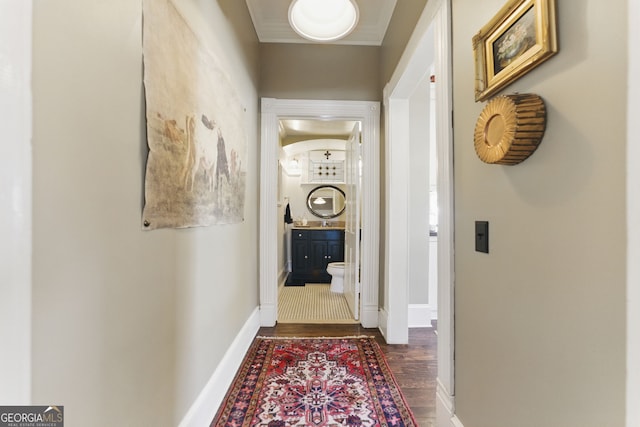 hall featuring baseboards, dark wood-type flooring, and ornamental molding