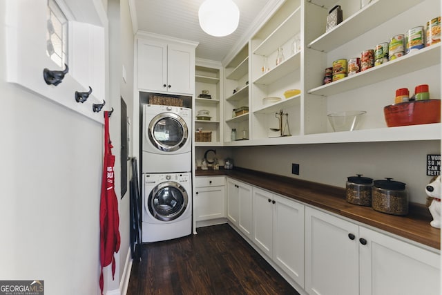 laundry area featuring stacked washer and dryer, cabinet space, crown molding, and dark wood-type flooring