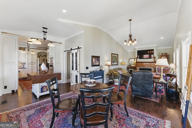 dining area featuring lofted ceiling, dark wood-style flooring, an inviting chandelier, and a barn door