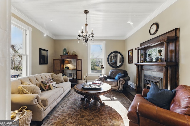 living room with crown molding, a fireplace, wood finished floors, baseboards, and an inviting chandelier