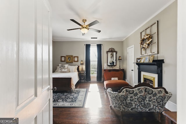 bedroom featuring a fireplace, wood finished floors, visible vents, baseboards, and ornamental molding