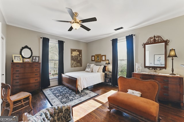 bedroom featuring ornamental molding, dark wood finished floors, visible vents, and a ceiling fan