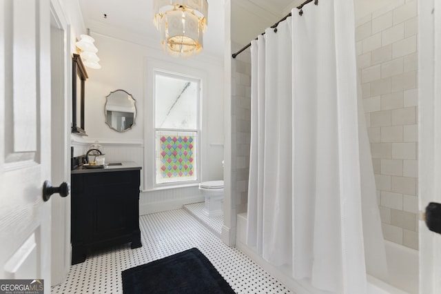 bathroom featuring toilet, a wainscoted wall, vanity, ornamental molding, and shower / bath combo