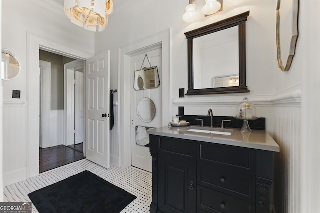 bathroom featuring a wainscoted wall, a decorative wall, crown molding, and vanity