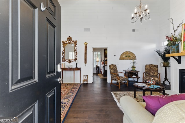 foyer entrance featuring a chandelier, dark wood-style flooring, a glass covered fireplace, and visible vents