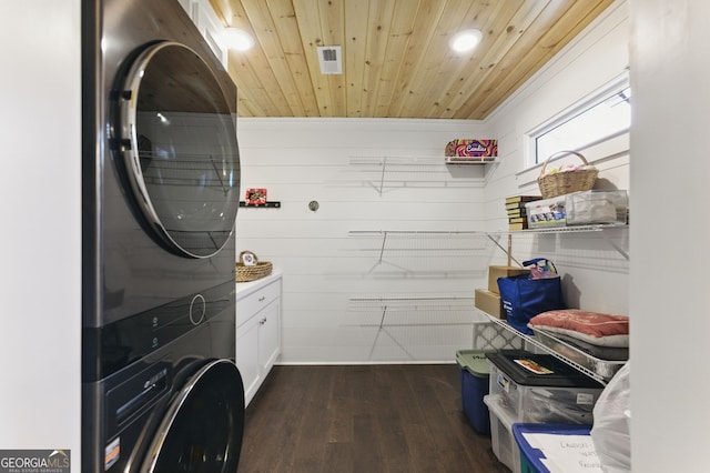 laundry area featuring stacked washer and dryer, cabinet space, visible vents, wooden ceiling, and dark wood-style floors