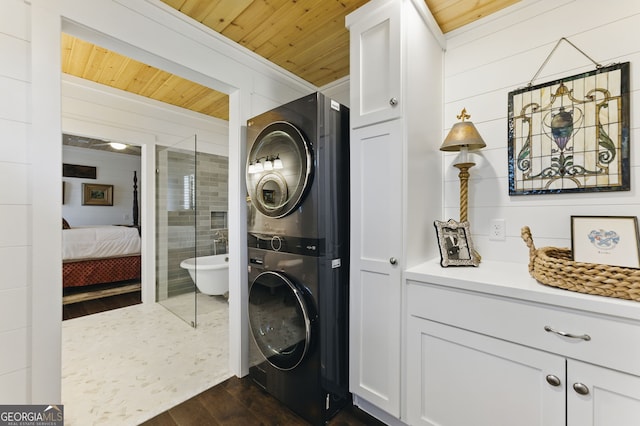 laundry area featuring stacked washing maching and dryer, wood ceiling, dark wood-type flooring, and wood walls