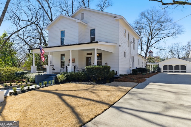 view of front of home featuring covered porch, an outdoor structure, and a detached garage