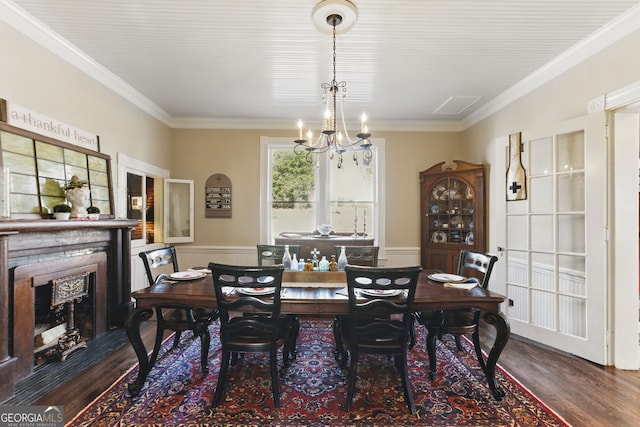 dining area featuring a chandelier, dark wood-style flooring, a wainscoted wall, and a fireplace