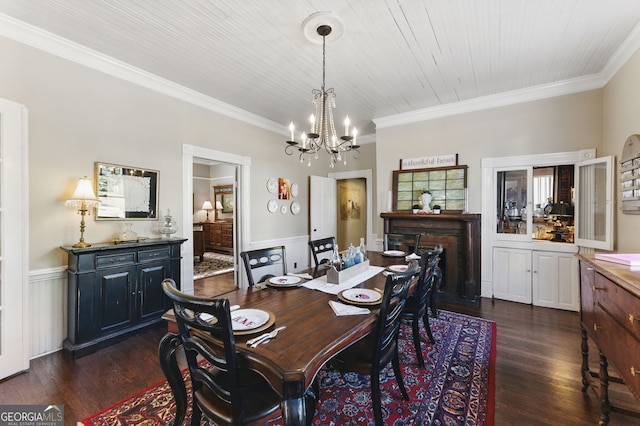 dining space with a wainscoted wall, crown molding, dark wood-style floors, and an inviting chandelier