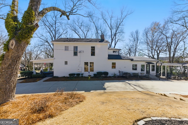 exterior space featuring driveway, a chimney, and fence