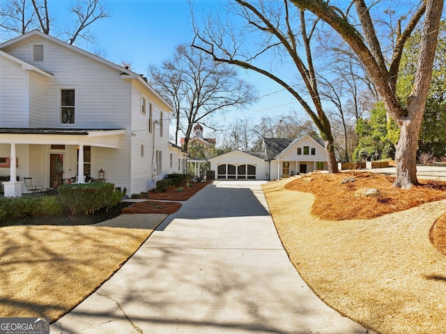 view of side of home featuring a garage, a porch, and an outdoor structure