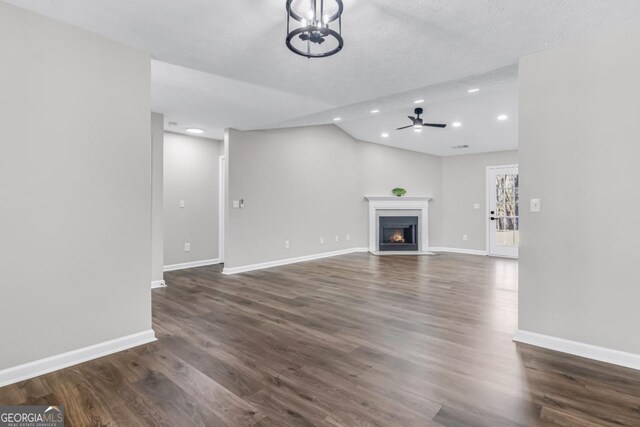 unfurnished living room with vaulted ceiling, dark wood-type flooring, and ceiling fan