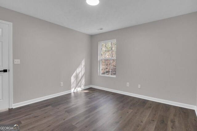 unfurnished room with dark hardwood / wood-style flooring