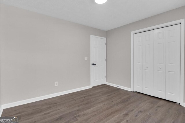 unfurnished bedroom with hardwood / wood-style flooring, a closet, and a textured ceiling