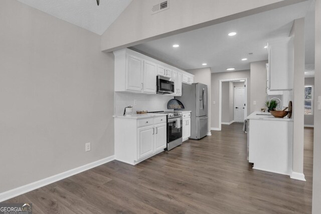 kitchen with stainless steel appliances, white cabinetry, lofted ceiling, and dark wood-type flooring