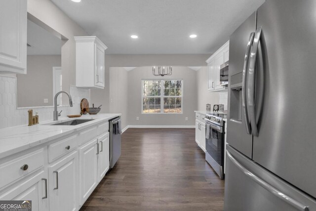 kitchen with sink, dark wood-type flooring, appliances with stainless steel finishes, light stone countertops, and white cabinets