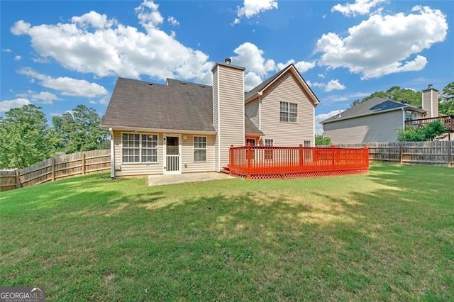 back of property with a wooden deck, a patio area, and a lawn