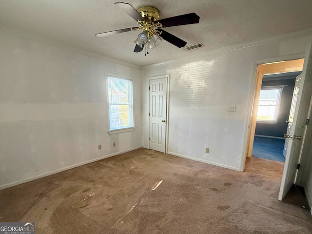 unfurnished bedroom with crown molding, ceiling fan, a textured ceiling, light carpet, and a closet