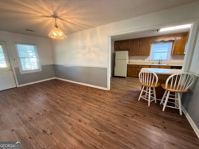 kitchen featuring dark wood-type flooring, sink, decorative light fixtures, white fridge, and backsplash