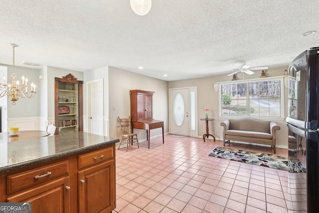 kitchen featuring pendant lighting, light tile patterned floors, dark countertops, brown cabinetry, and freestanding refrigerator