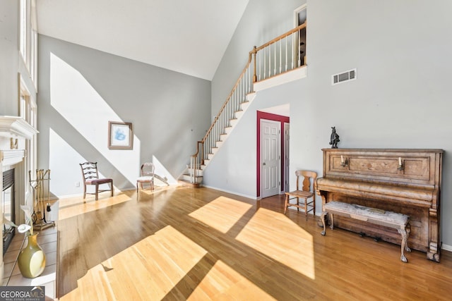 entryway with wood finished floors, visible vents, baseboards, stairway, and a glass covered fireplace