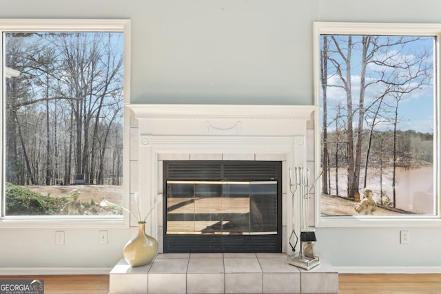 interior details featuring a tiled fireplace, wood finished floors, and baseboards