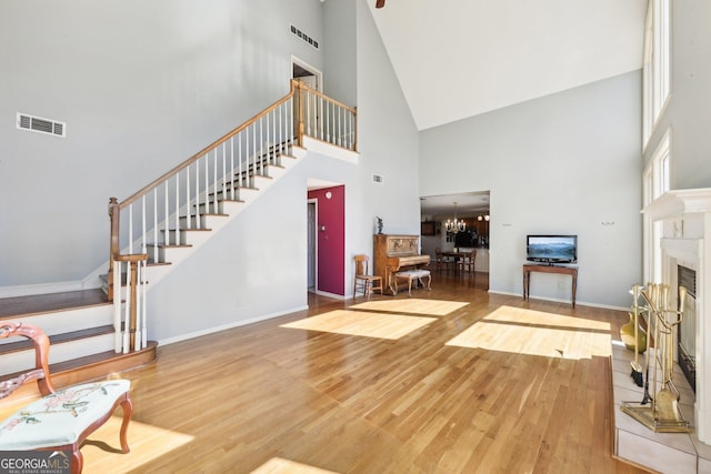 living room featuring a chandelier, a tiled fireplace, wood finished floors, and visible vents