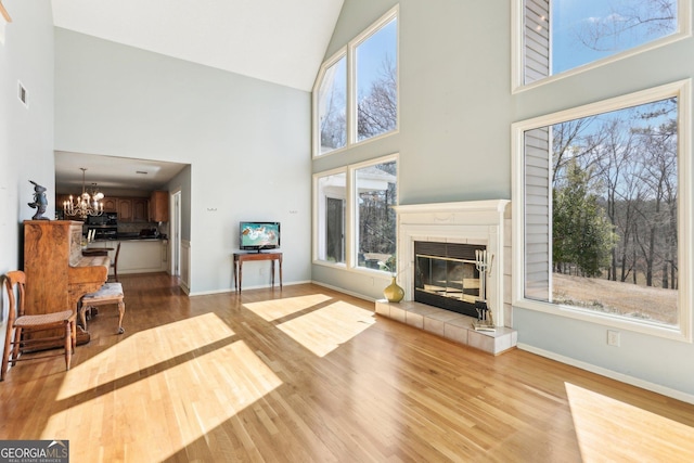 living area featuring light wood-style flooring, a fireplace, visible vents, baseboards, and an inviting chandelier