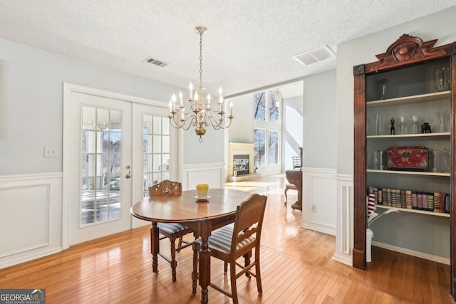 dining area featuring a textured ceiling, light wood-type flooring, a glass covered fireplace, and a wealth of natural light