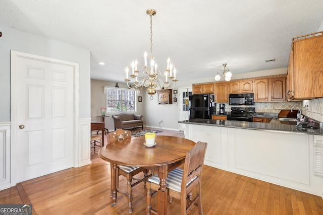 dining room featuring light wood-style floors, visible vents, a chandelier, and baseboards