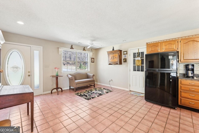 interior space with light tile patterned floors, a textured ceiling, dark countertops, and freestanding refrigerator